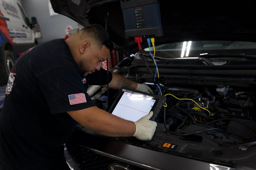 C & A Auto Body Shop technician running a computer diagnostic scan on a car